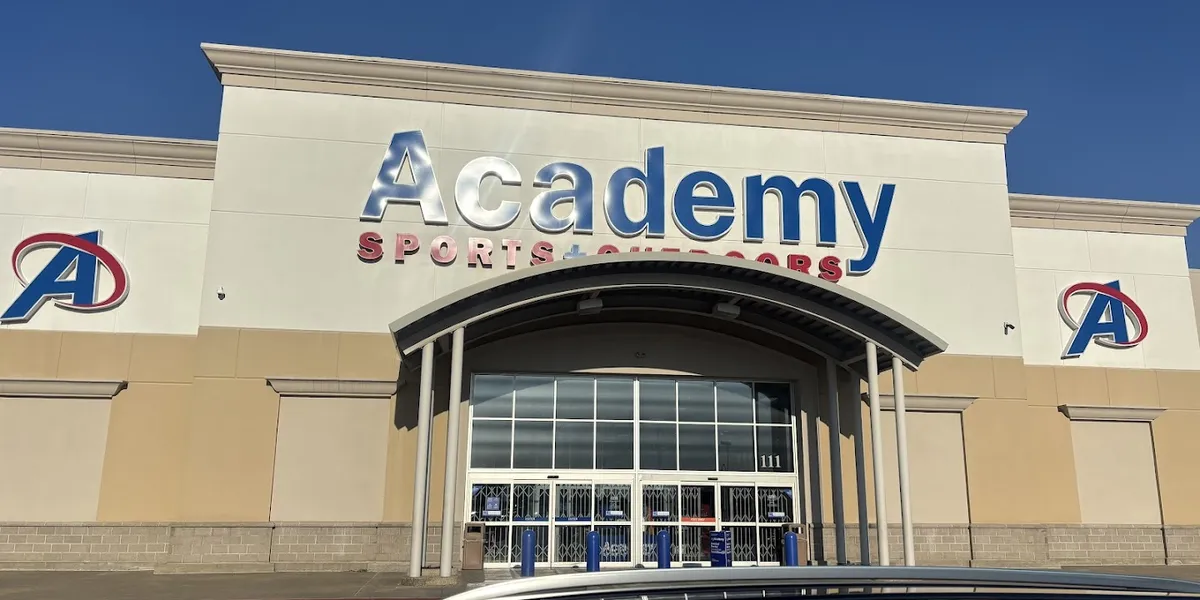 Spacious sporting goods retail floor with well-stocked women's footwear section, multiple checkout lanes, and organized...