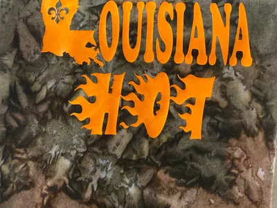 Compact gift shop displaying colorful Greek apparel and custom t-shirts with consultation space where Rick assists customers.