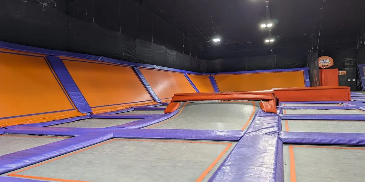 Expansive indoor trampoline facility with wall-to-wall jumping surfaces, foam pits, and dedicated party areas filled with...