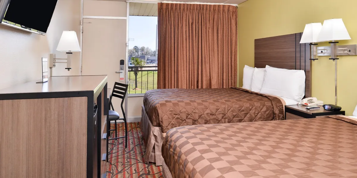 Exterior of a roadside motel with basic signage, parking lot for trucks, and row of ground-floor room entrances.