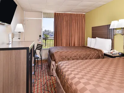 Exterior of a roadside motel with basic signage, parking lot for trucks, and row of ground-floor room entrances.