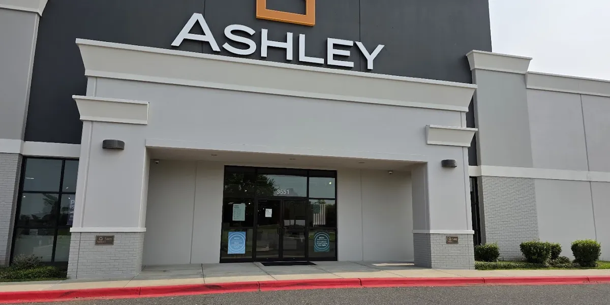 Spacious, well-organized furniture showroom with bedroom sets and living room displays arranged in comfortable browsing...