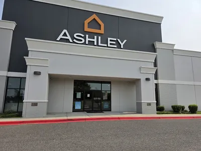 Spacious, well-organized furniture showroom with bedroom sets and living room displays arranged in comfortable browsing...