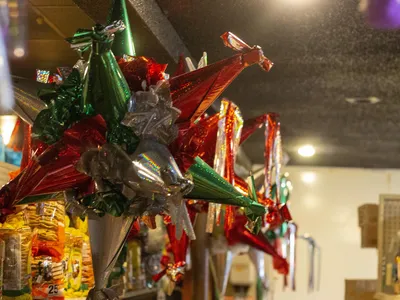 Colorful Mexican grocery store with produce displays, imported snacks, and a deli counter serving traditional dishes in a...