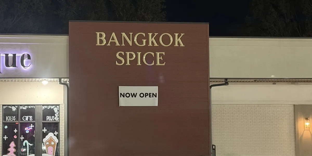 Renovated Thai restaurant interior with original booth seating, dark lighting, and traditional table settings in a quiet...