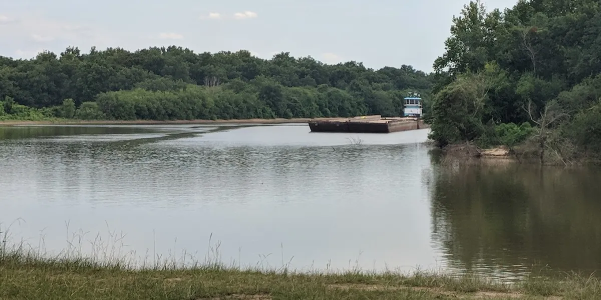 Boat launch ramp descending into the Ouachita River with surrounding grassy picnic areas, parking lot, and latrines...