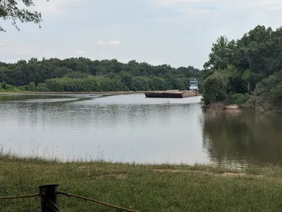 Boat launch ramp descending into the Ouachita River with surrounding grassy picnic areas, parking lot, and latrines...