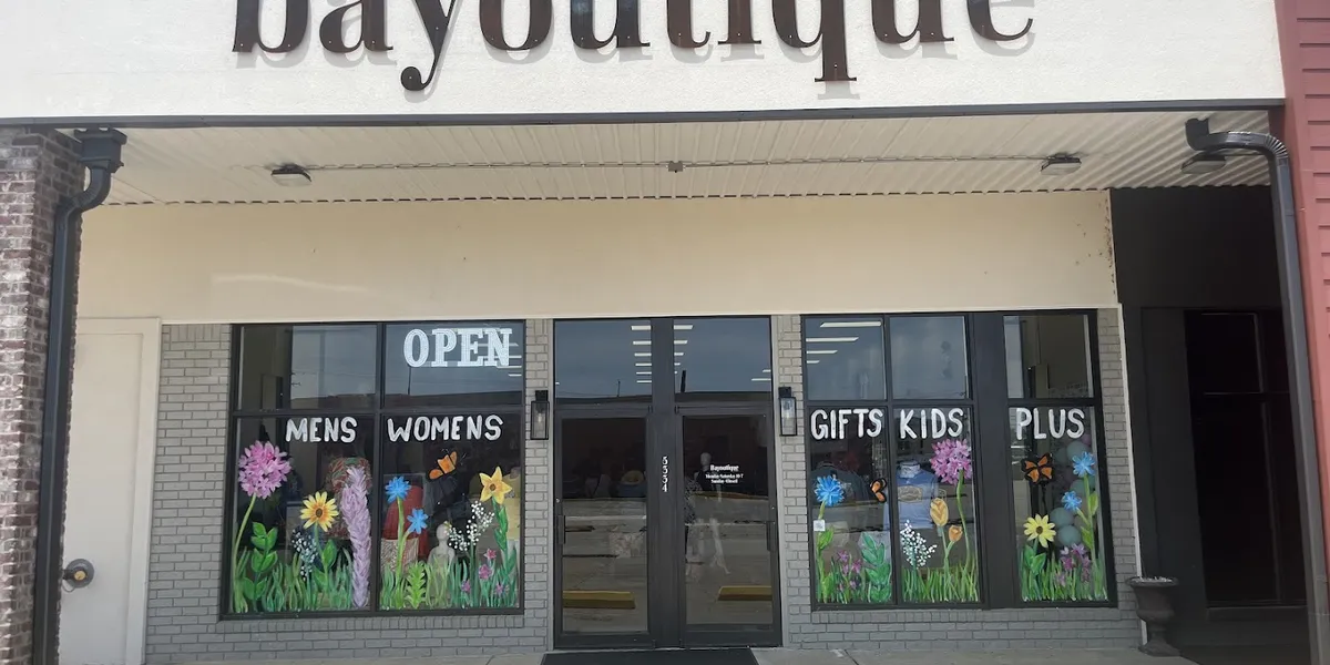 Spacious boutique with well-organized clothing racks, jewelry displays, and outdoor-themed men's section in a bright,...