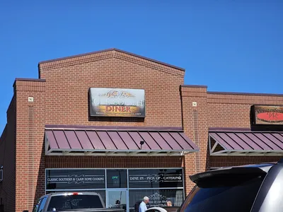 Bustling authentic Southern diner with tables of comfort food plates, friendly servers refilling drinks, and a crowd of...