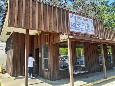 Spacious soul food restaurant with tables of diverse patrons enjoying generous plates of Southern cooking in a relaxed,...