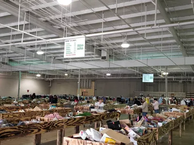 Spacious warehouse-style discount store with rows of large merchandise bins where shoppers dig for unexpected bargains on...
