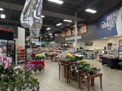 Bright, well-organized grocery store with clean aisles, stocked shelves, and an inviting bakery counter featuring custom...