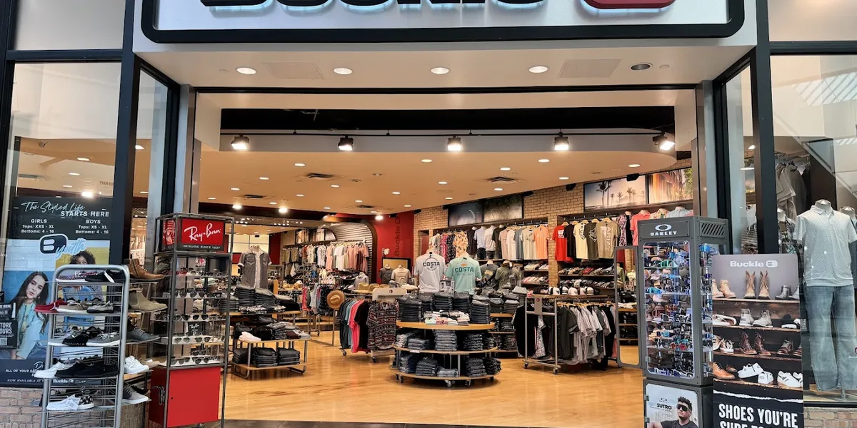 Neatly organized premium denim and casual clothing displays at Buckle's bright retail space with attentive staff and...