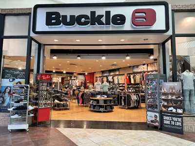 Neatly organized premium denim and casual clothing displays at Buckle's bright retail space with attentive staff and...