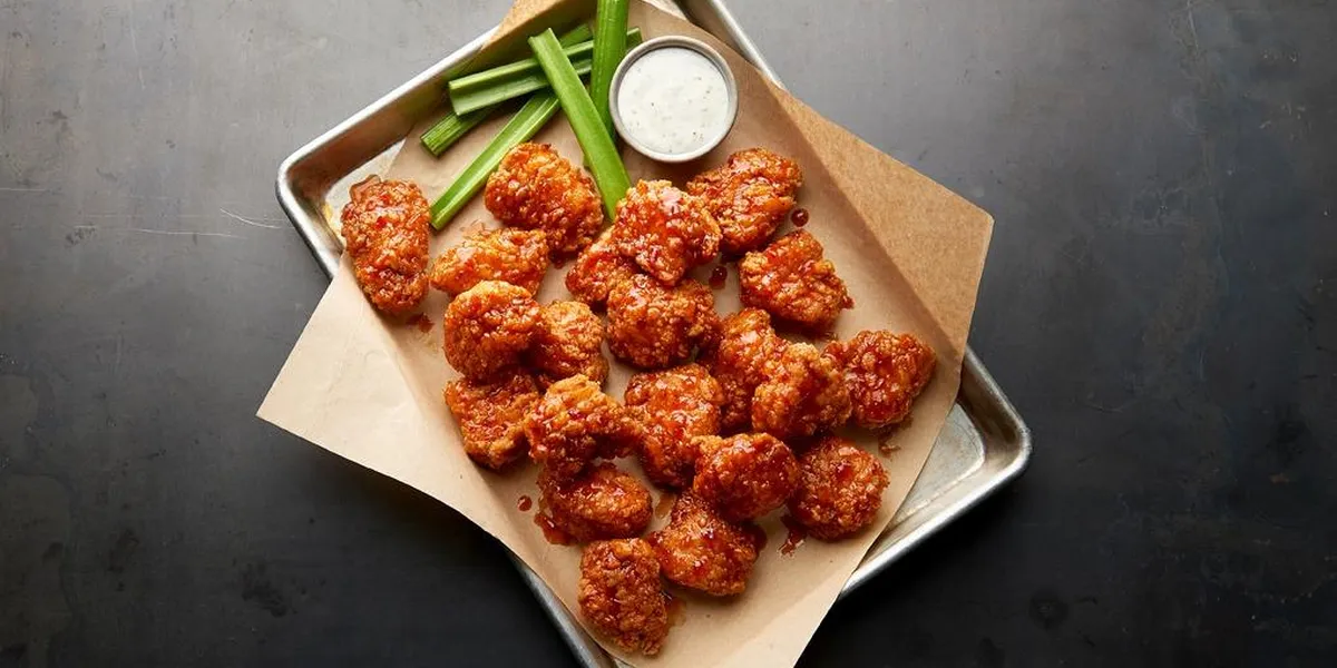 Sports bar interior with TV screens, wing baskets, and beer taps, featuring both indoor dining and outdoor seating area...