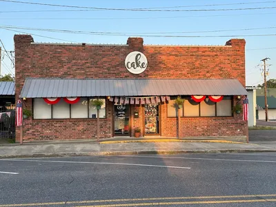 Charming bakery counter with fresh cookies and cakes displayed under glass, cozy seating area, and view of Trenton...