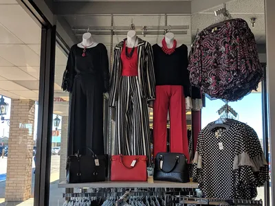 Brightly lit women's clothing store with neatly organized racks divided between plus and regular sizes, accessory...