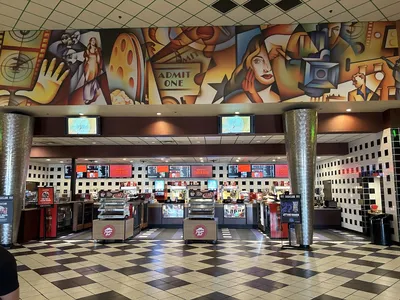 Multi-screen Cinemark Tinseltown theater with spacious parking lot, illuminated marquee, and clean lobby area for moviegoers.