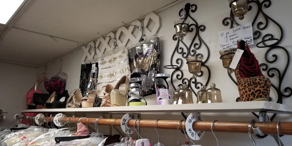 Neatly organized consignment shop with racks of quality secondhand clothing, formal dresses, and a clean, boutique-like...