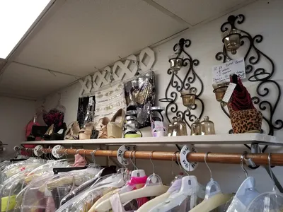 Neatly organized consignment shop with racks of quality secondhand clothing, formal dresses, and a clean, boutique-like...