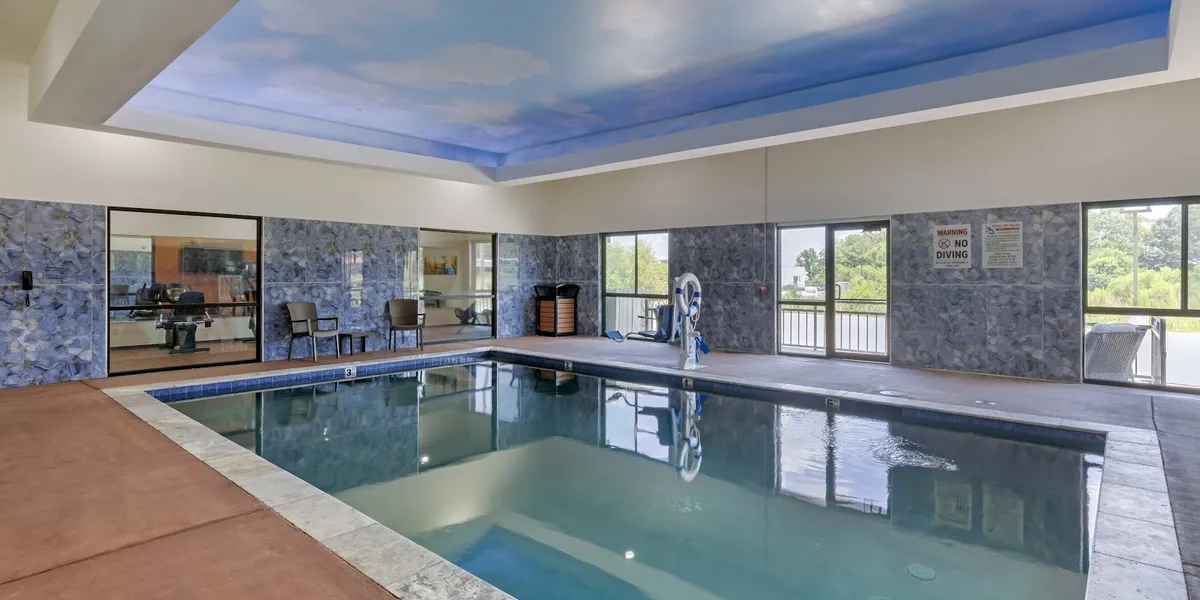 Contemporary hotel exterior with well-maintained pool area, featuring accessible entrance and outdoor seating near the...