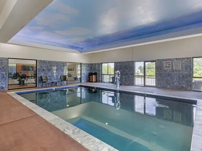 Contemporary hotel exterior with well-maintained pool area, featuring accessible entrance and outdoor seating near the...