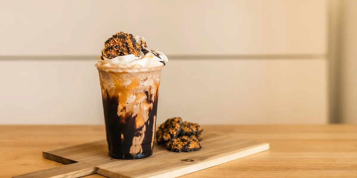 Cozy interior of Corner Coffee + Provisions featuring study tables, drive-thru window, and counter displaying açaí bowls...