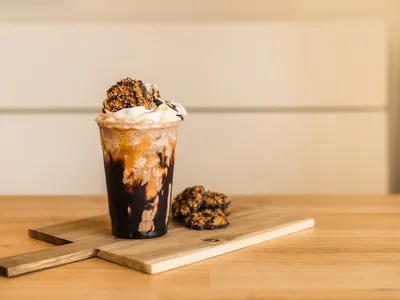 Cozy interior of Corner Coffee + Provisions featuring study tables, drive-thru window, and counter displaying açaí bowls...