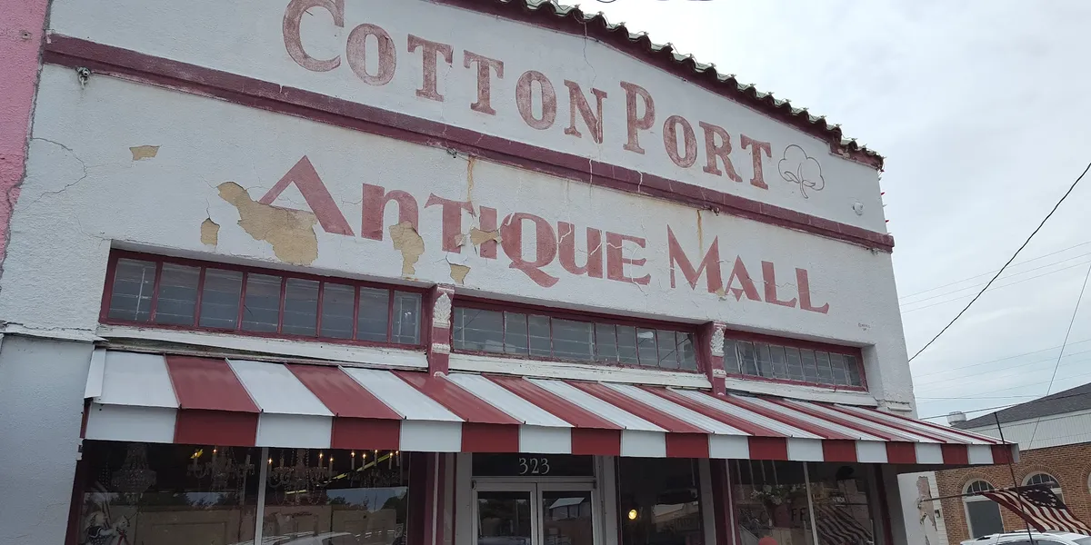 Spacious antique mall with rows of glass display cases showcasing coins and collectibles amid vintage furniture in a...