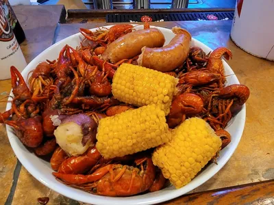Bustling seafood restaurant with tables of steaming crawfish platters where locals gather weekly during the seasonal...