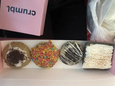 Bright, modern cookie shop with display case showcasing oversized, freshly-baked specialty cookies in Crumbl's signature...