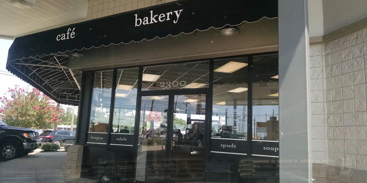 Bright convenience store interior with food counter serving coffee and grab-and-go meals, featuring clean displays of...