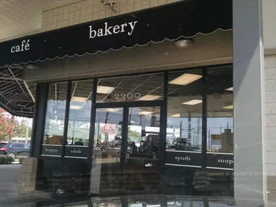 Bright convenience store interior with food counter serving coffee and grab-and-go meals, featuring clean displays of...