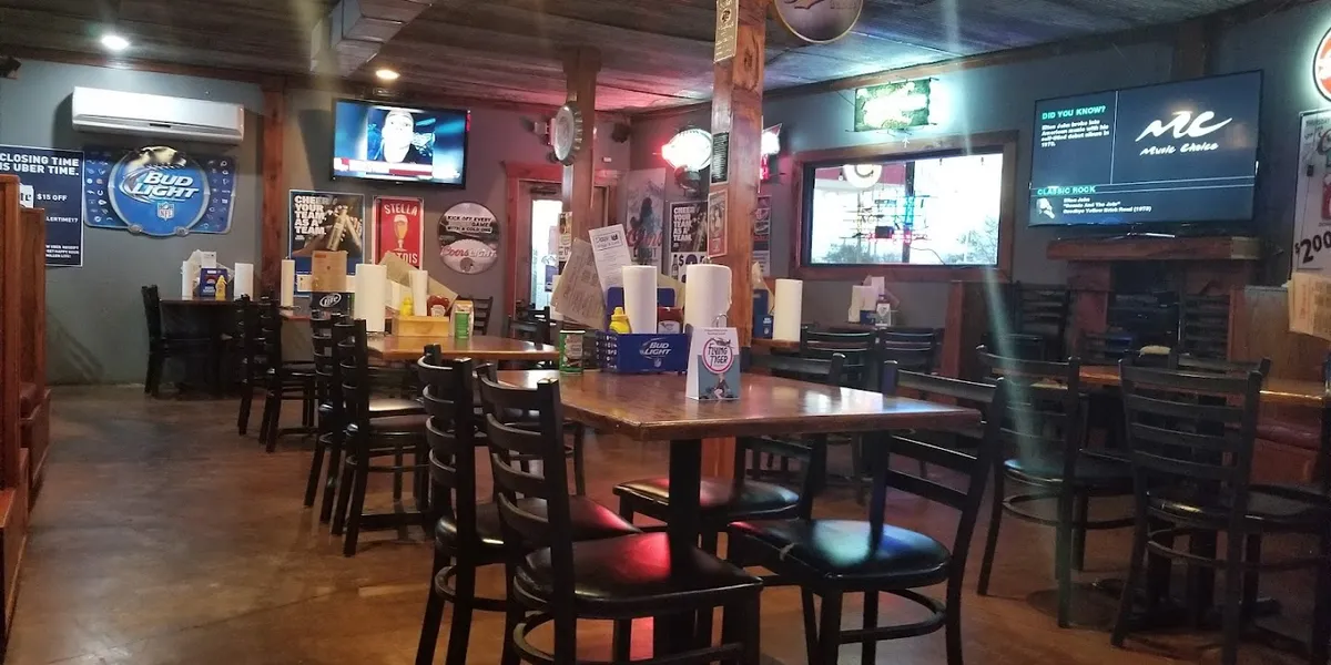 Casual wing restaurant with dimly lit interior featuring table seating, serving signature buffalo ranch wings and...