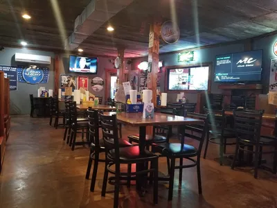 Casual wing restaurant with dimly lit interior featuring table seating, serving signature buffalo ranch wings and...