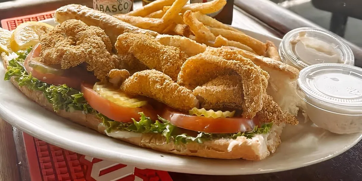 Casual seafood restaurant with patio seating, serving steaming platters of dark-shelled crawfish and seafood baskets in...