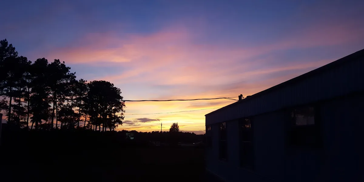 Rows of clean, maintained mobile homes at Deer Run Community with paved roads, parking spaces, and interstate visible in...