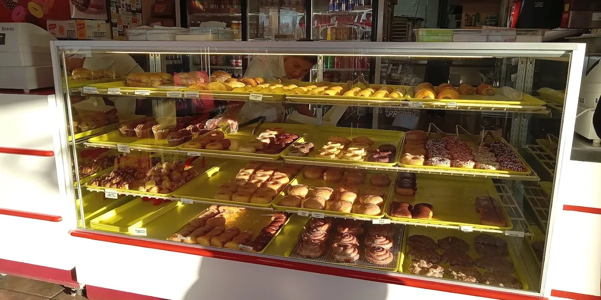 Compact donut shop with drive-thru window displaying freshly-made pastries and breakfast items popular with college students.