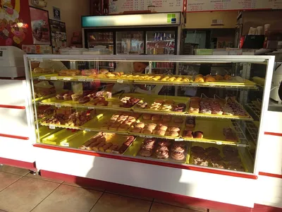 Compact donut shop with drive-thru window displaying freshly-made pastries and breakfast items popular with college students.