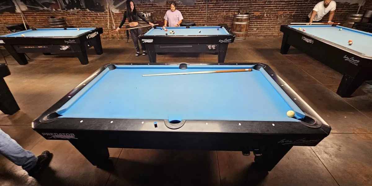 Interior of Downtown Billiards showing pool tables, bar area, and chic decor with outdoor space visible through windows