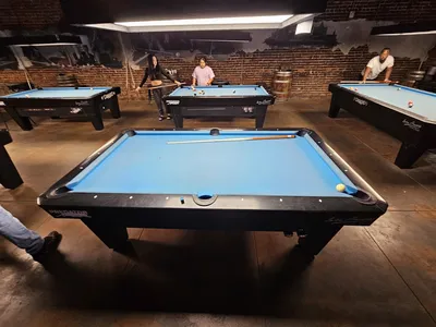 Interior of Downtown Billiards showing pool tables, bar area, and chic decor with outdoor space visible through windows