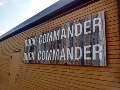 Rustic storefront of Duck Commander with hunting-themed decor, merchandise displays, and TV show memorabilia in a casual...