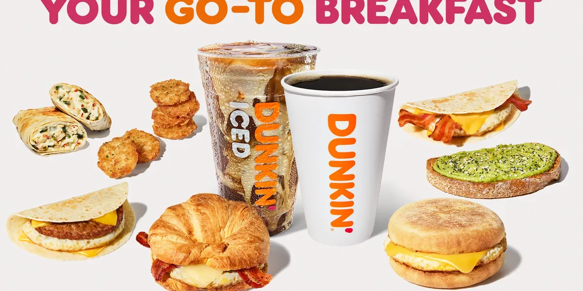 Bright Dunkin' storefront on Cypress Street with drive-thru lane, outdoor seating area, and signature pink and orange...