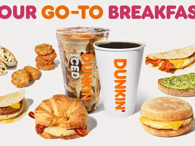 Bright Dunkin' storefront on Cypress Street with drive-thru lane, outdoor seating area, and signature pink and orange...