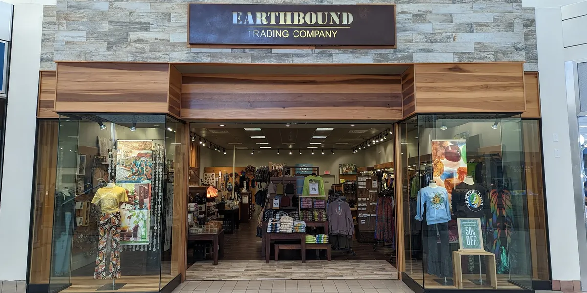 Neatly organized bohemian retail space with displays of crystals, spiritual items, and colorful hippie-style clothing in...