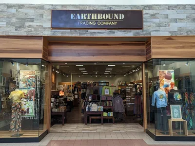 Neatly organized bohemian retail space with displays of crystals, spiritual items, and colorful hippie-style clothing in...