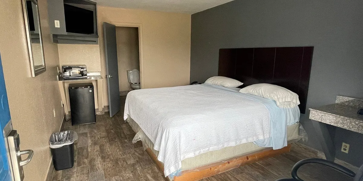 Exterior view of Economy Inn Monroe showing recently renovated motel rooms with window-service reception and parking...