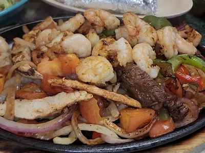 Cozy Mexican restaurant with outdoor seating area, bustling with regular patrons enjoying signature nachos and steak dishes.