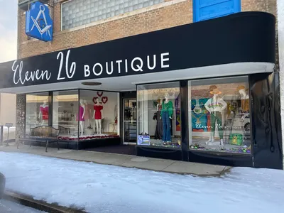 Elegantly arranged women's boutique with open floor displays of dresses, shoes and jewelry, featuring curtained changing...