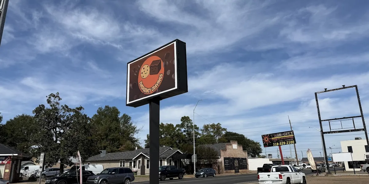 Cozy bakery counter displaying oversized cookies and specialty brownies with outdoor seating area and coffee service station.